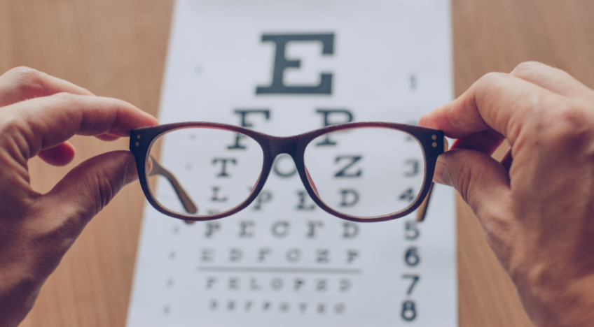 i think i could be dead - glasses held over an eye chart